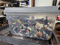 Plastic tote filled with assorted LEGO bricks and pieces of various colors and sizes.