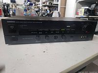 Front view of Onkyo stereo preamp showing control buttons, LED indicator, and missing knob shaft