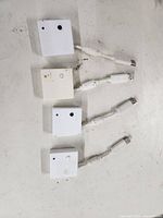 Four white square-shaped wireless USB dongles with short attached USB cables laid out on a flat surface.