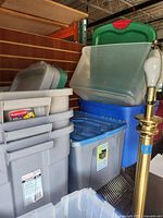 Photo showing multiple storage totes stacked with visible lids in gray, blue and green. One tote has a red green lid.