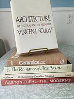 Stack of five hardcover books showing spines and one book displayed on stand