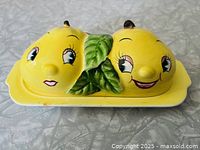 front angle showing anthropomorphic pear lid on base