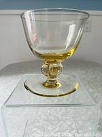Side and angled view of hand-blown honey-coloured cocktail glass showing tapered bowl, four-lobed ball stem and circular base