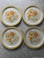 Set of four Hearthside Sunshine Flower stoneware plates arranged in a 2x2 pattern showing full floral design and yellow rims.