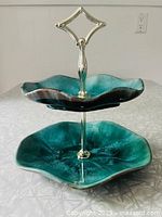 Two-tier Blue Mountain Pottery serving dish shown from top angle, highlighting scalloped edges and blue/brown glaze with glossy finish.