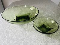 Large and small green glass chip and dip bowls with square bases on a table.