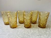 Set of six honey gold vintage Anchor Hocking juice glasses arranged in two rows, showing textured bark pattern and weighted bottoms.