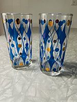 Pair of clear vintage glasses showing blue diamond netting design with gold circles from the 1960s