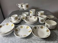 Full view of the dishware pieces including cups, saucers, bowls, small plates, and cream and sugar set displayed on table.