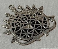 Close-up front view of silver Hittite sun disk pendant showing geometric cut-out pattern and ray extensions