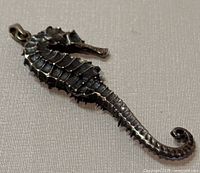 Close-up photo of the front side of a 925 silver seahorse pendant showing detailed body and curled tail.