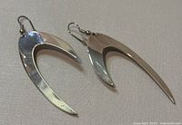 Top view of the pair of crescent-shaped sterling silver earrings showing surface reflection and shape