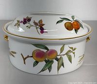 Front view of the lidded porcelain tureen, showing the hand-painted fruit decoration including peaches and blackberries with gold trim on the rim and handles.