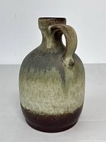 Front and side angled view of a Mid-century modern West German textured glaze jug vase with round bulbous shape and handle.