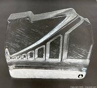 Front view of clear glass paperweight with modernist etched design of an elevated structure featuring arches.