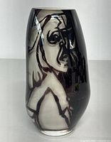 Front view of the black and white hand blown art glass vase showing the abstract face design on the surface.