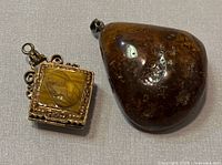 Photo of both natural amber pendant and vintage camo onyx locket pendant side by side.