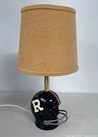 Full view of the desk lamp with football helmet base and beige fabric lampshade attached, showing the overall appearance and condition.