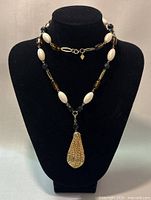 Necklace displayed on black jewelry stand showing full length of necklace and pendant.