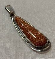 Front view of teardrop-shaped brown aventurine set in polished 925 silver pendant.