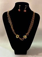 Front view of necklace and earrings displayed on black bust, showing copper chain with two large enamel beads and matching earrings with smaller enamel beads.
