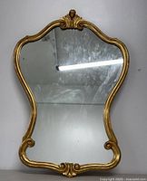 Front view of vintage Italian gilt wall mirror showing ornate gold frame with shell motifs at top and bottom.