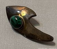 Front view of vintage Navajo sterling silver brooch with green malachite stone set in bezel, showing patina and shape.