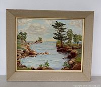 Front view of framed vintage original landscape painting depicting coastal scene with trees, rocks, water, and sailboats on the horizon.