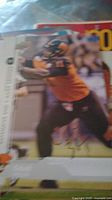 Blurry autographed football card showing a player in black and orange uniform with signature