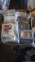 Top view of a box with multiple stacks of hockey cards bundled and loose; some cards in sealed plastic bags and holders.