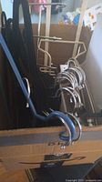 Photo showing a box filled with multiple black plastic hangers and several shiny silver metal hangers.