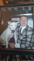 Close-up view of the framed photo showing Don Cherry wearing a plaid jacket with the dog sitting beside him