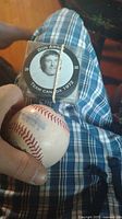 Photo of a hand holding a used baseball and a hockey puck in original packaging with Don Awrey's image and Team Canada 1972 text.