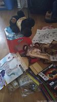 Overview of the assortment including plush bears on top of a container, model kits, coloring sheets, and other toys scattered on floor.