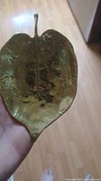 Top view of the vintage solid cast linden leaf metal dish showing detailed leaf veins and the stem with patina and wear.