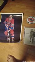 Photo showing a large color poster of a hockey player in red Canadiens gear, a round Montreal Canadiens logo pin-back button, and a black and white photo of a hockey player.