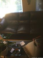 3-seater brown leather sofa with padded cushioned seats, backrest and arms shown in living room setting.