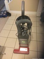 Top view of Lux Veridian corded upright vacuum cleaner with hose attachment coiled on the front and power cord wrapped behind the handle.
