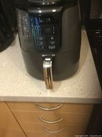 Front view of black Ninja electric air fryer showing digital control panel and silver handle on the drawer/basket