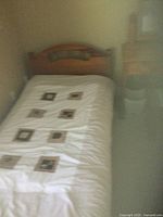 Single bed frame with mattress featuring a white cover with square pattern