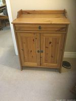Front view of traditional wooden cupboard showcasing drawer and two doors with metal hardware and natural wood finish.