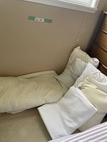 Queen size bed with damask bedspread partially visible and four white pillows arranged at the head of the bed.