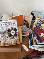 Full view of cookbooks arranged on a table, showing two wooden cookbook stands, multiple cookbooks including The Canadian Living Cookbook and recipe folder