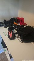 Overview of the lot including aqua shoes, gloves, hand warmers, seat cushion, and gaiters on a white surface