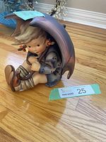 Side view of seated girl figurine under umbrella on hardwood floor