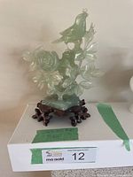 Full view of the carved jadeite bird figurine with a rose flower and leaves on a wooden base, showing overall item.