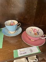 Pair of pink and blue china tea cups with saucers on wooden surface