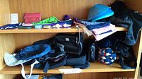 Shelf with assorted small handbags, wallets, scarves, gloves, and a blue sun visor hat