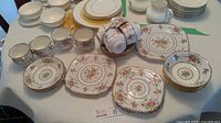 Overview of entire china set including teacups, saucers, and plates arranged on a table with white tablecloth