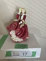 Front view of the Royal Doulton "Top of the Hill" figurine showing detailed red dress with white lace and hat.